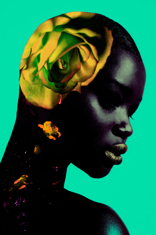 Portrait of a black model in profile with her dark skin contrasting a collage of yellow roses on her natural, bald head.