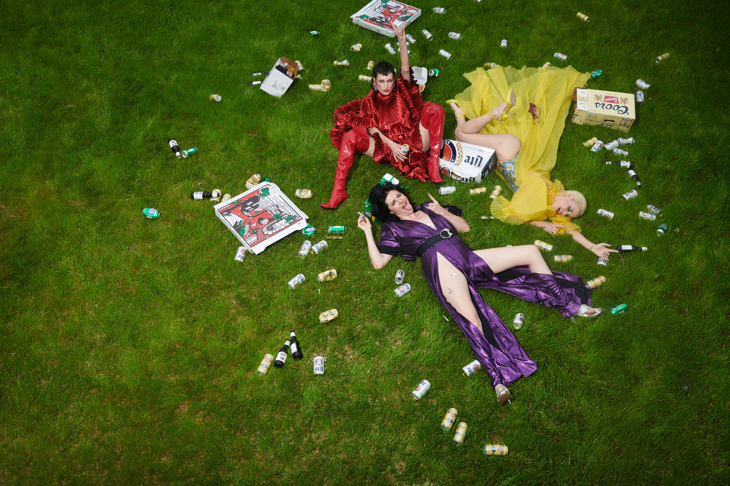cool punk Girls laying in green grass front lawn after party with beer cans everywhere and pizza boxes party animals hungover