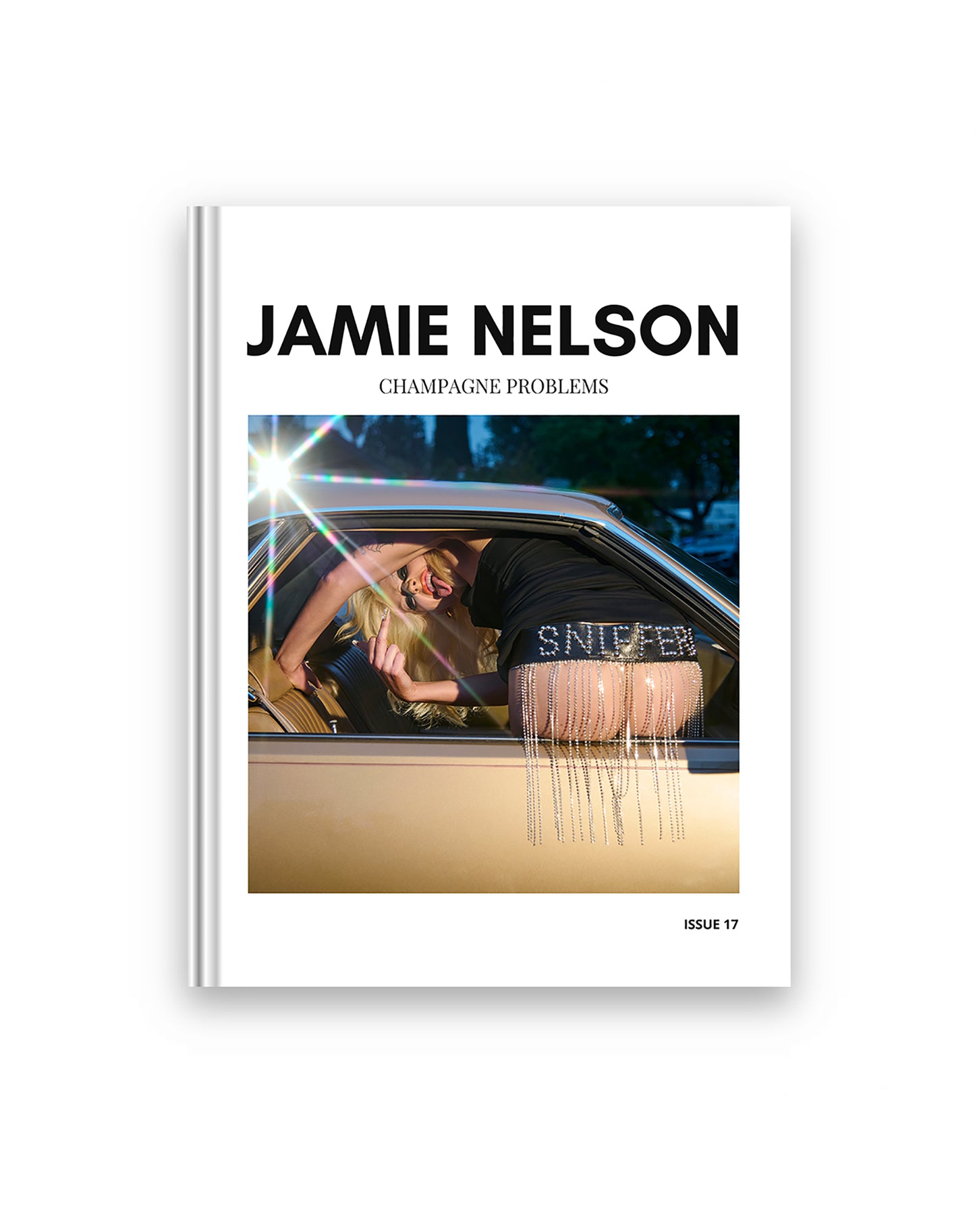 A magazine cover of a woman flipping off the camera as she shows her butt out of a gold vintage car window. The words 'Jamie Nelson' and 'Champagne Problems' text appear on the cover.