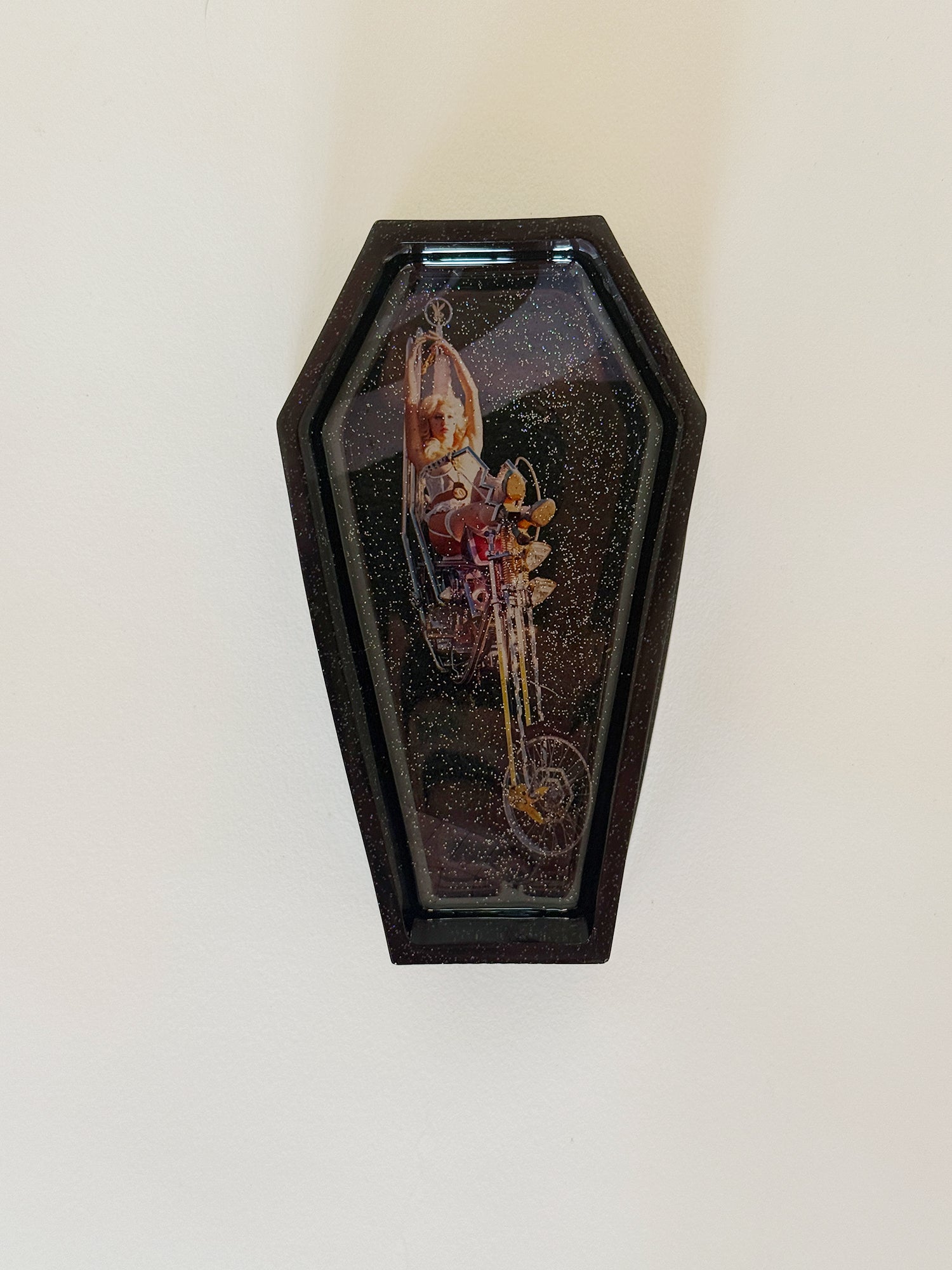 Decorative coffin-shaped box with a small figurine inside on a white background