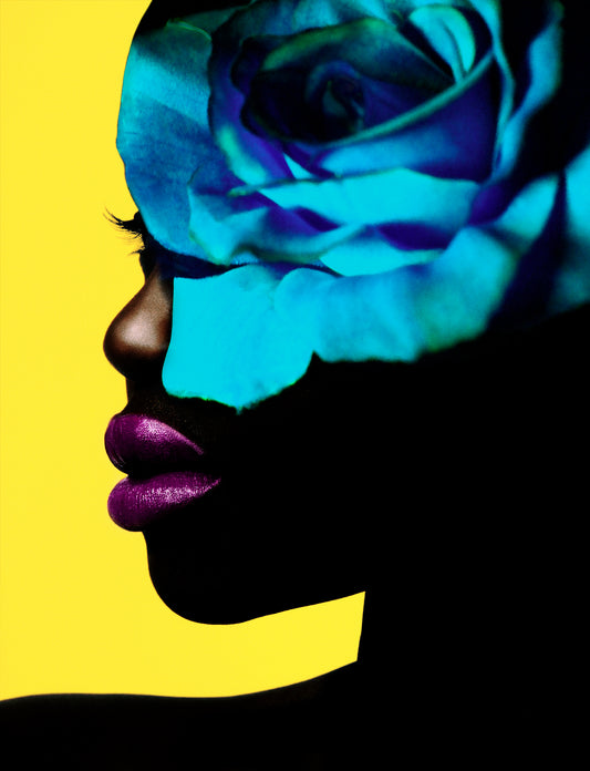 Portrait side profile of a black woman in silhouette with purple lipstick and a blue rose collage on her head with a vibrant yellow background.