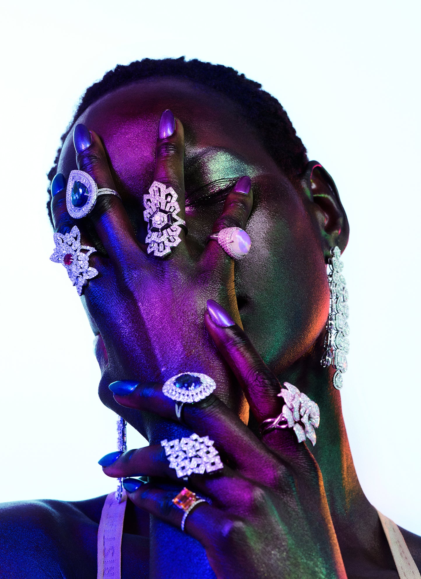 Black woman with hands dripping in fancy fine jewelry and covering her face. Brands include Cartier, Tiffany, Cartier, Boucheron, Van Cleef & Arpels, Chopard, David Yurman, Bvlgari.