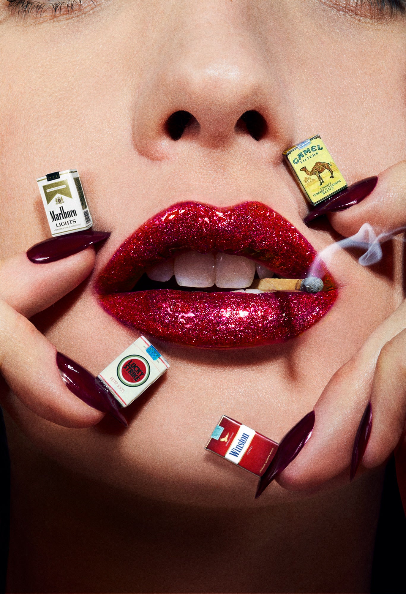 Macro photography of woman with ruby red glitter lips with smoking matchstick in her teeth surrounded by miniature dollhouse cigarettes in multiple brands on her fingernails