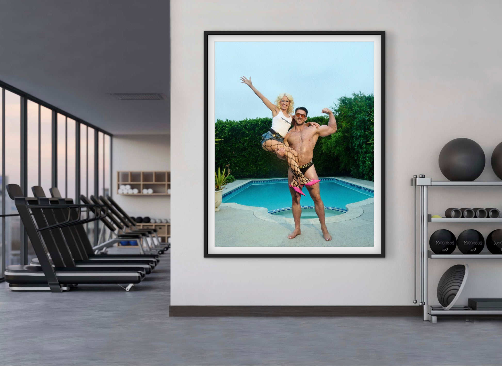 Framed photograph of a couple by a pool in a modern indoor setting with exercise equipment.