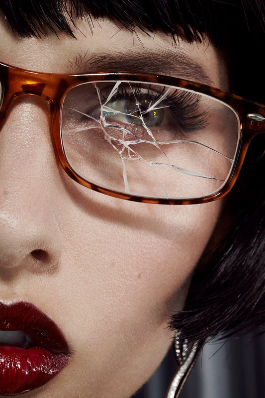 close-up of girl female model with black bob and broken prescription tortoise shell eye glasses