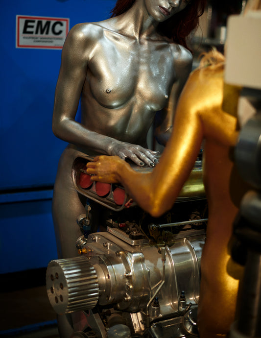 Metallic and gold sculpture of women interacting with mechanical components, with an EMC logo in the background.