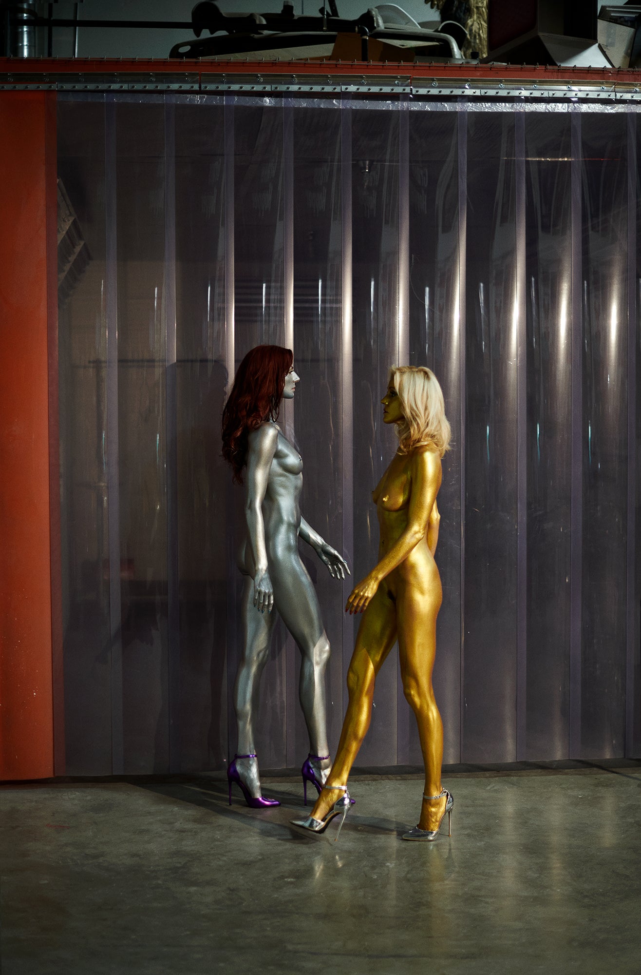 Two naked fembot style women walking in an industrial office location.