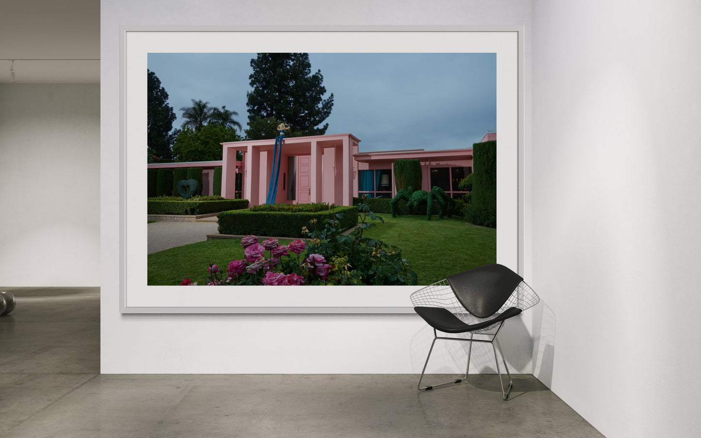 Framed photograph of a blonde woman (Amy Taylor of Amyl and the Sniffers) flexing while sitting on Jamie Nelson's iconic pink palace rootfop. She is wearing the world's longest jeans that stretch from the roof down to the ground.