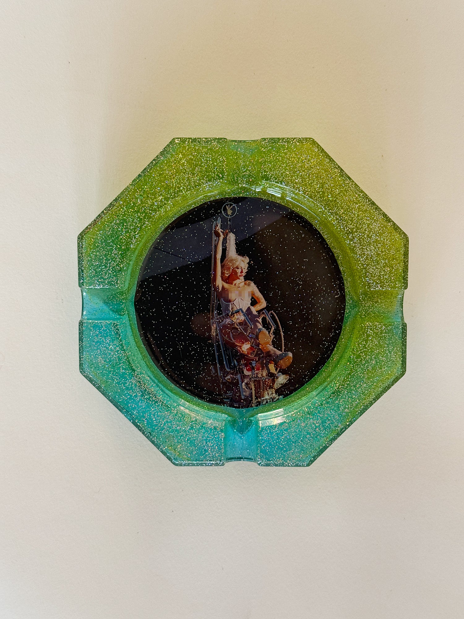 Decorative wall piece with a green and blue frame on a white wall