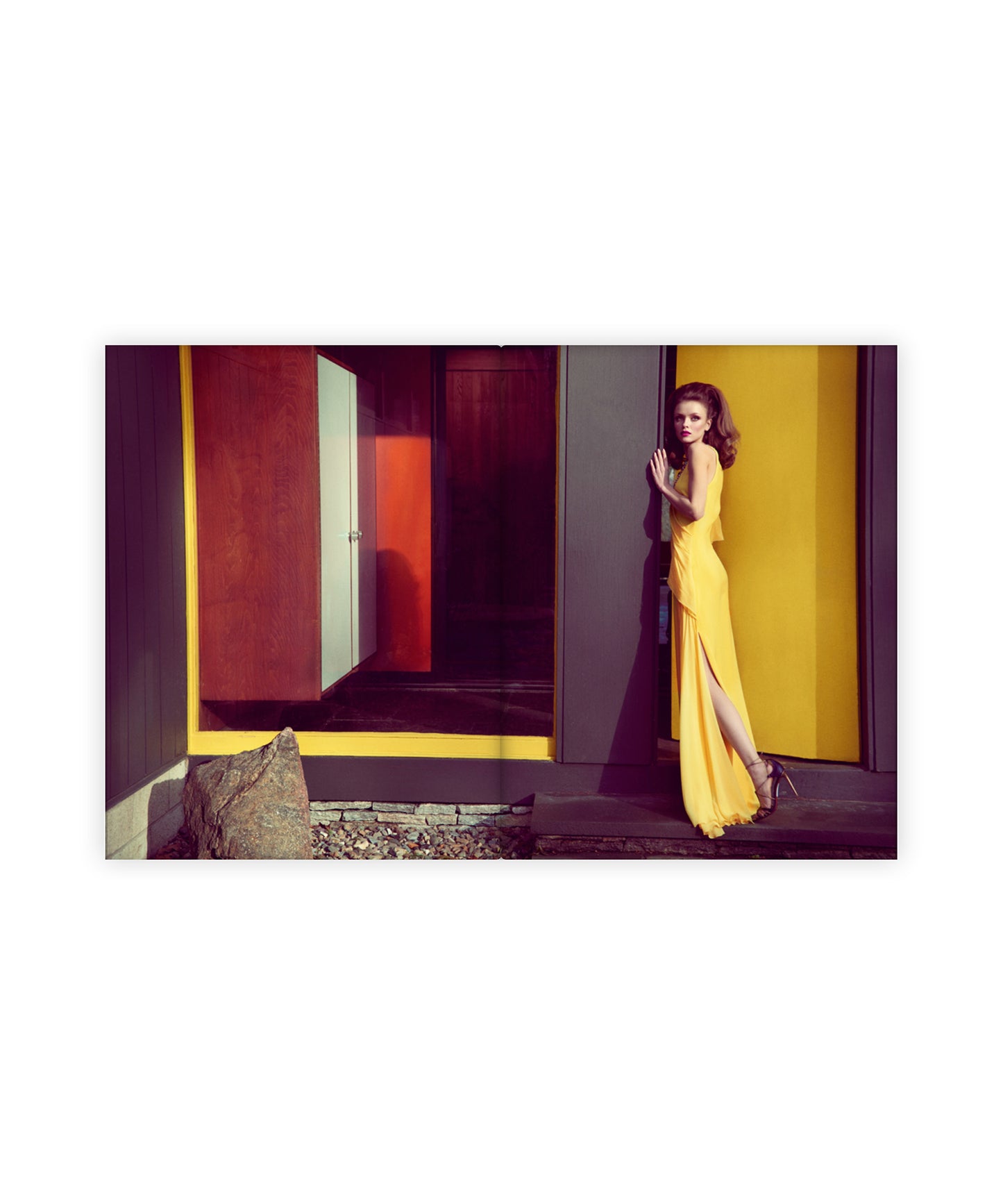 Woman in a yellow dress standing in a colorful geometric room.