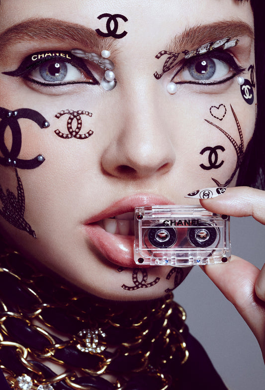 Woman covered in Chanel designer face stickers and tattoos while holding cassette tape by Los angeles based beauty photographer Jamie Nelson.