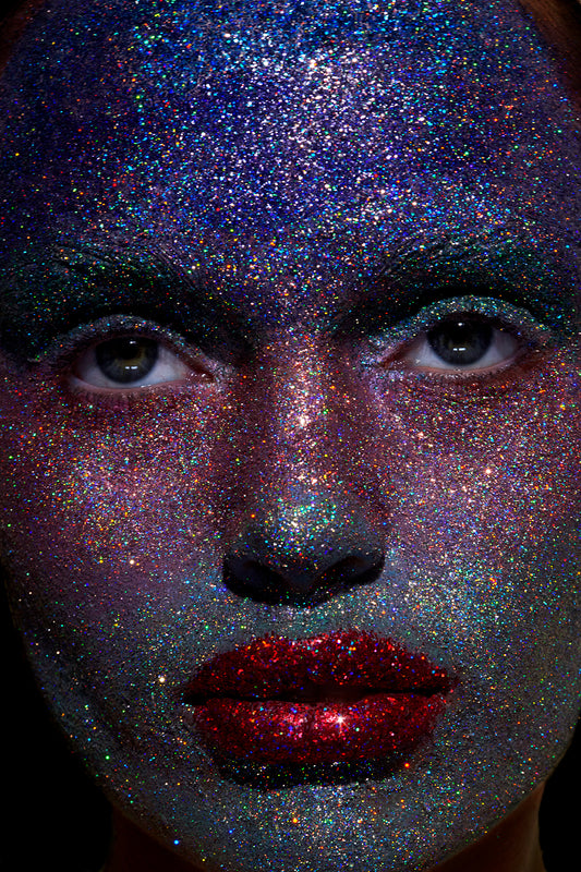 A woman with a full face of sparkly glitter ombre galactic makeup and ruby red glitter lips.