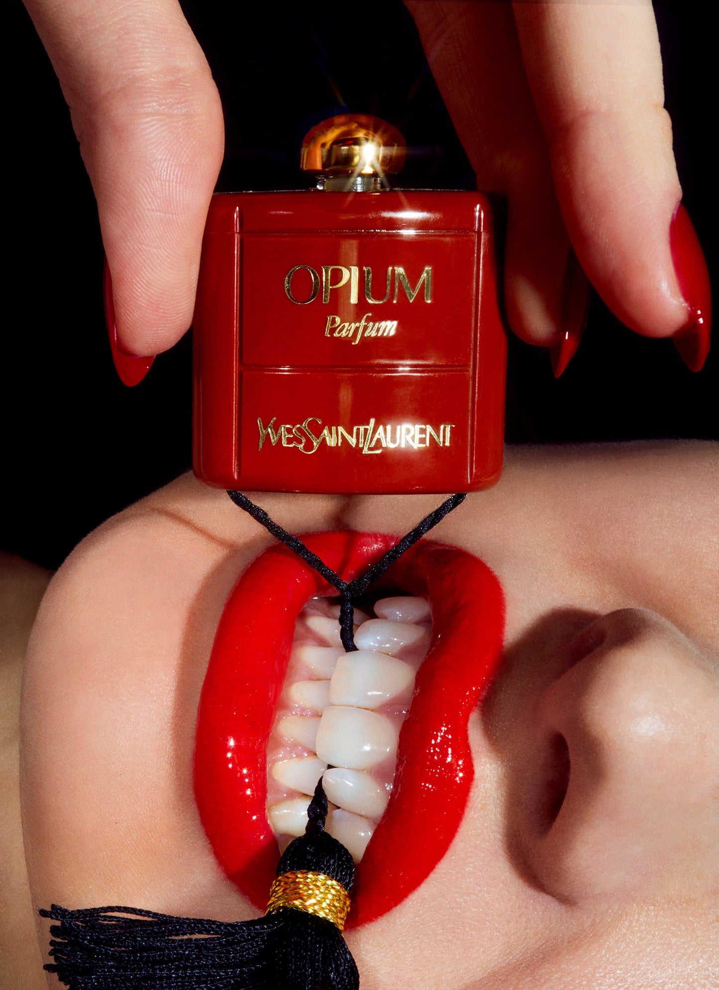 close up macro photo of woman clenching teeth with miniature opium yves saint laurent parfum bottle in her mouth