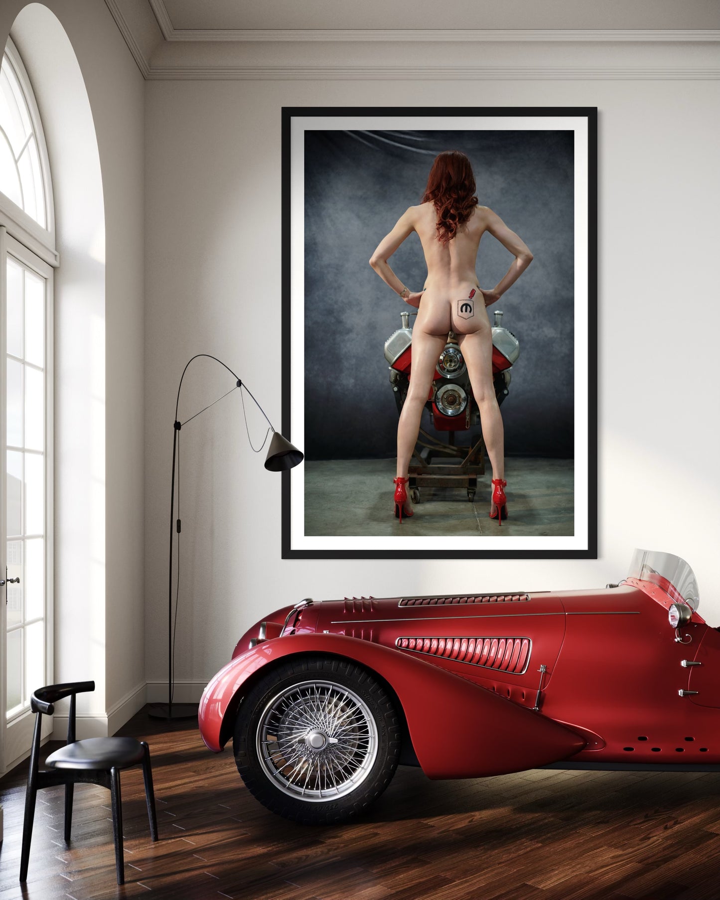 Framed artwork of a nude woman wearing only red heels standing in front of a Mopar engine in a fancy room with a red classic car.