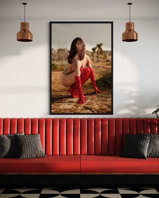 Framed artwork of a person in a red dress on a wall above a red sofa with black and gray cushions.