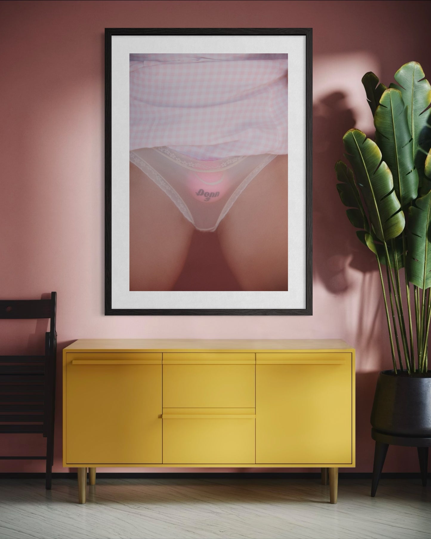 Pink room with a large framed artwork of a woman's crotch. She is wearing sheer underwear that expose a pink tennis ball stuffed down her underwear.