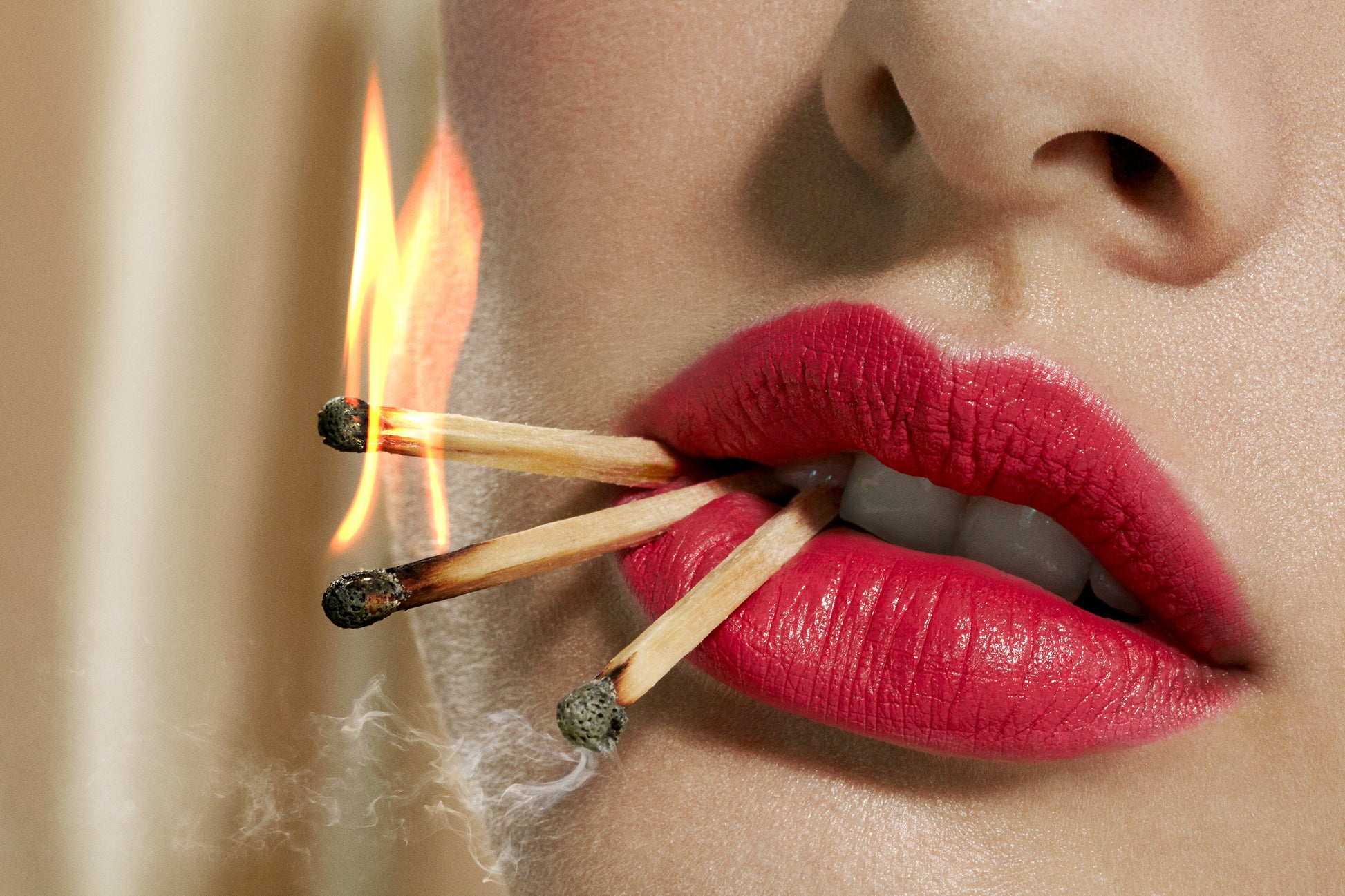Close-up macro of female model woman's lips with matchsticks in mouth on fire photographed by Los Angeles based fine artist Jamie Nelson.