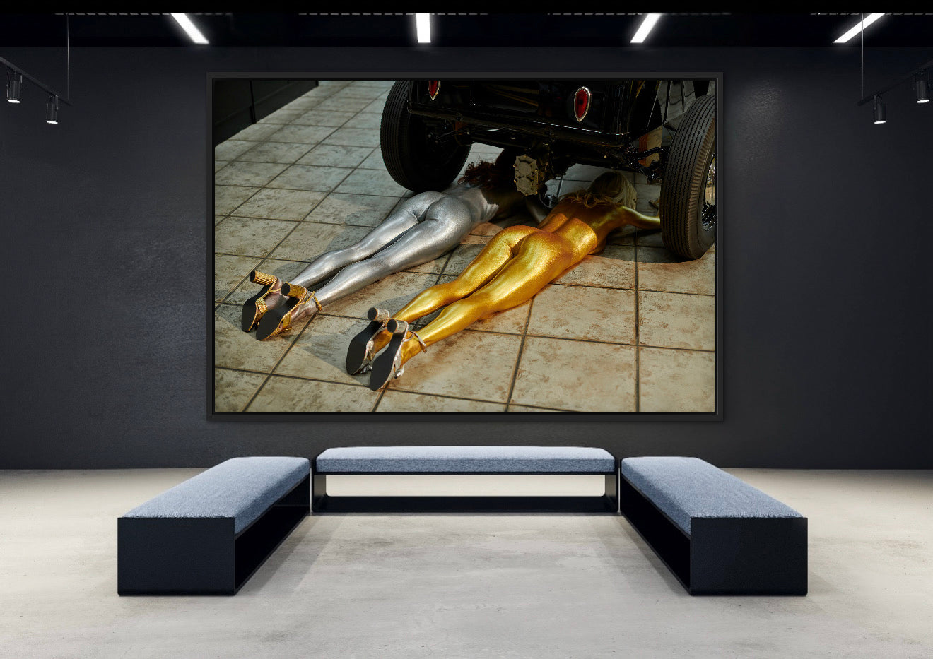 Modern interior with a large framed artwork of legs under a car on a dark wall.