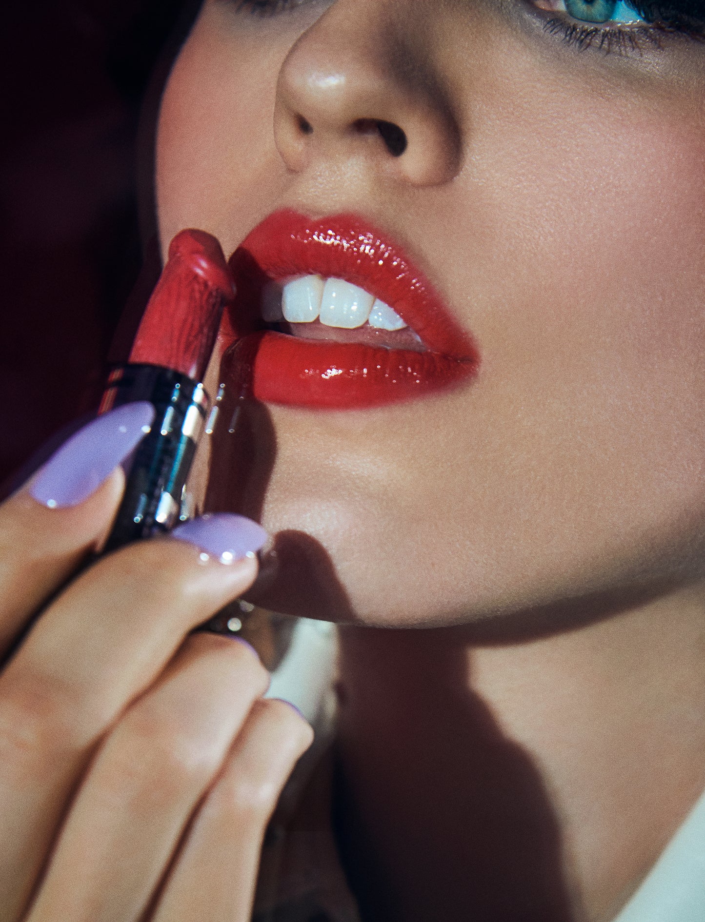 Close-up beauty editorial fine art photography of 80s style woman with long lilac nails applying phallic penis shaped red lipstick