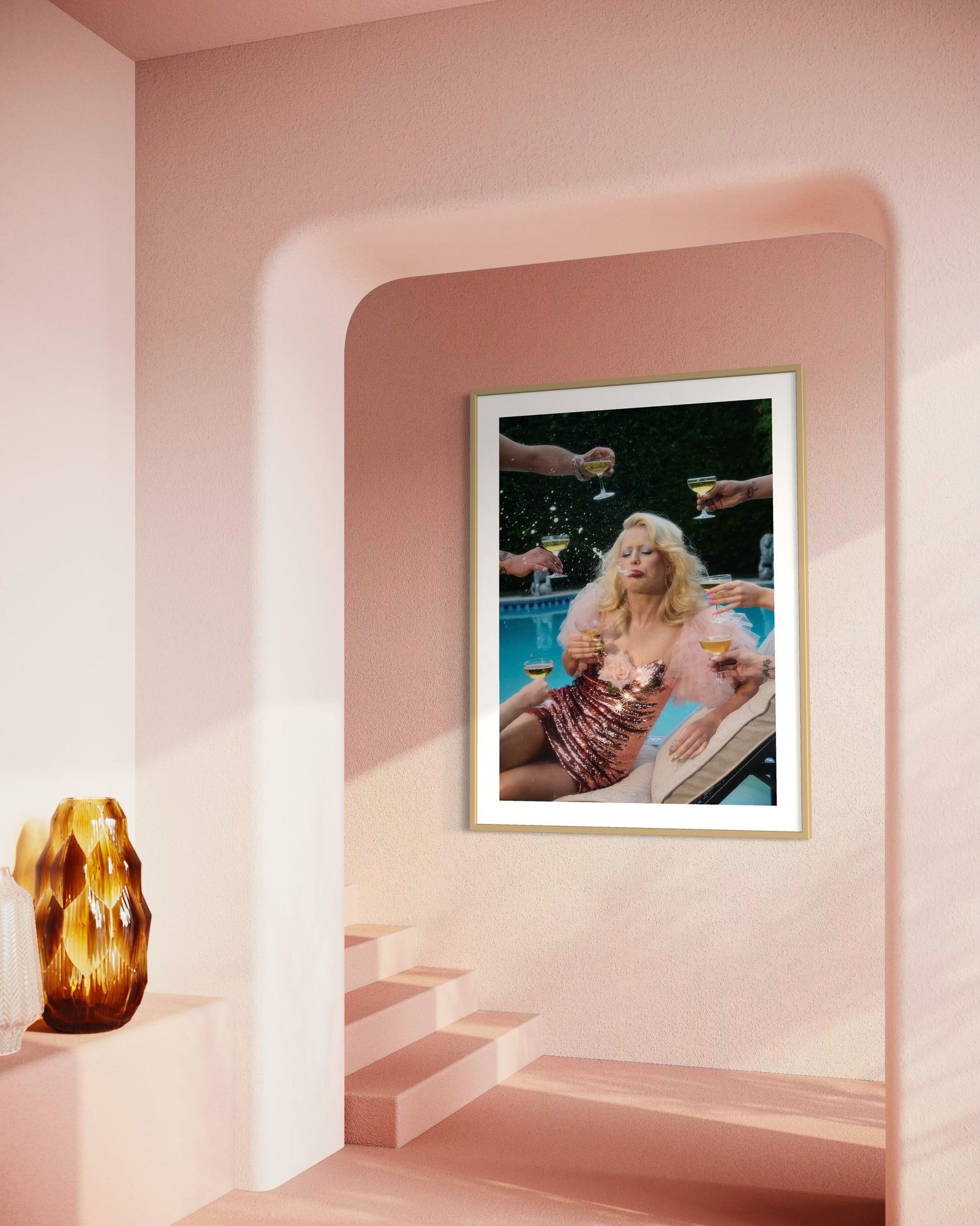 Framed artwork of a woman by a pool with people around, displayed in a room with pink walls and a vase on a shelf.