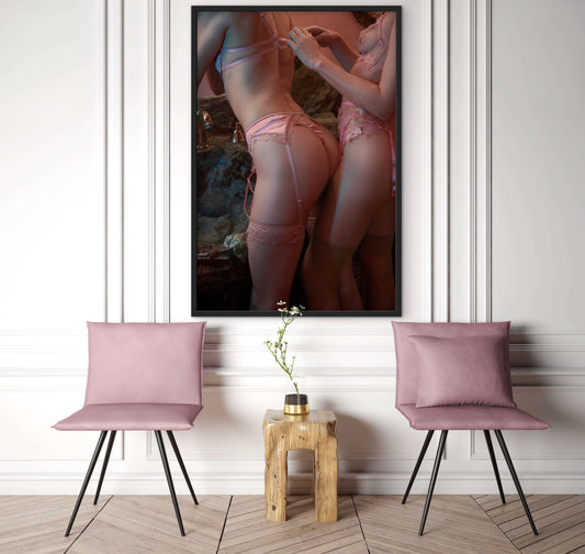 Two pink chairs with a wooden table and a framed artwork on a white wall.