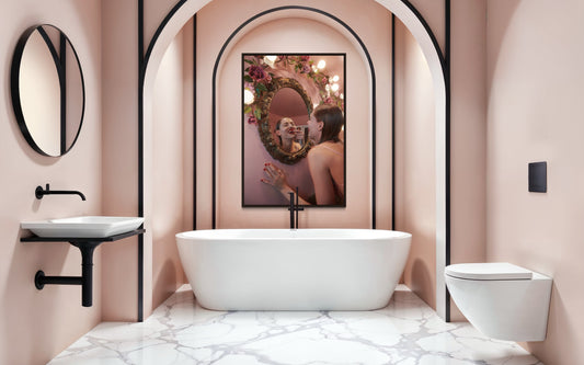 Modern bathroom with a freestanding bathtub, sink, and toilet against a pink wall.
