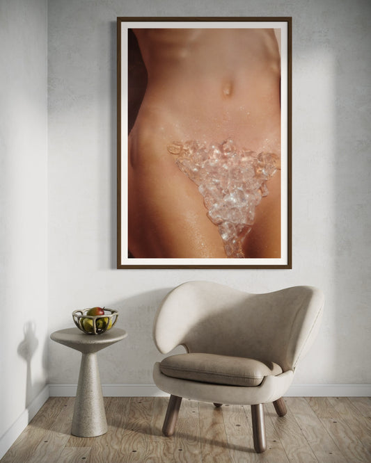 Framed artwork of a woman's back with crystals on a wall above a chair and side table.
