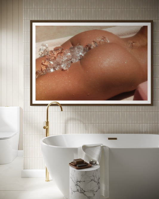 Framed artwork of a person in a bathtub with ice cubes in a bathroom setting.