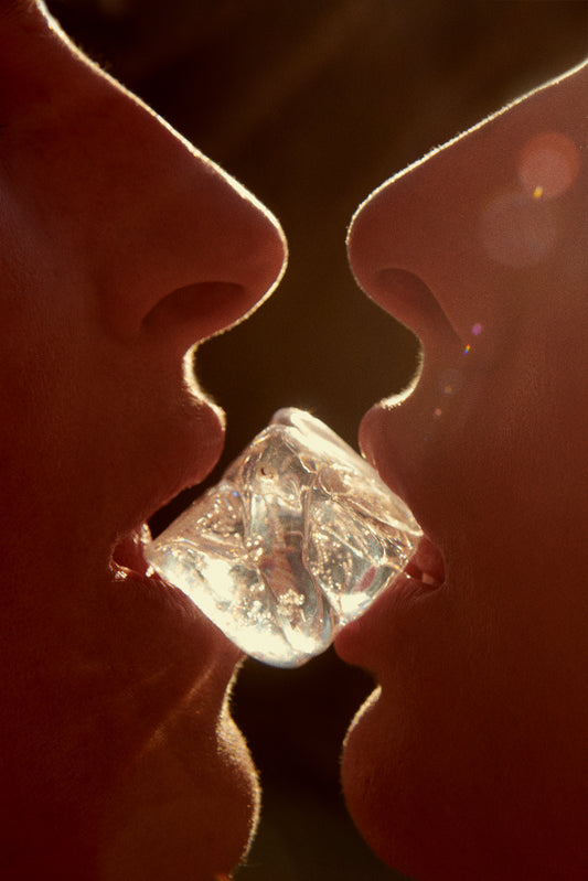 Two faces close together with an ice cube between them, symbolizing love and luxury.