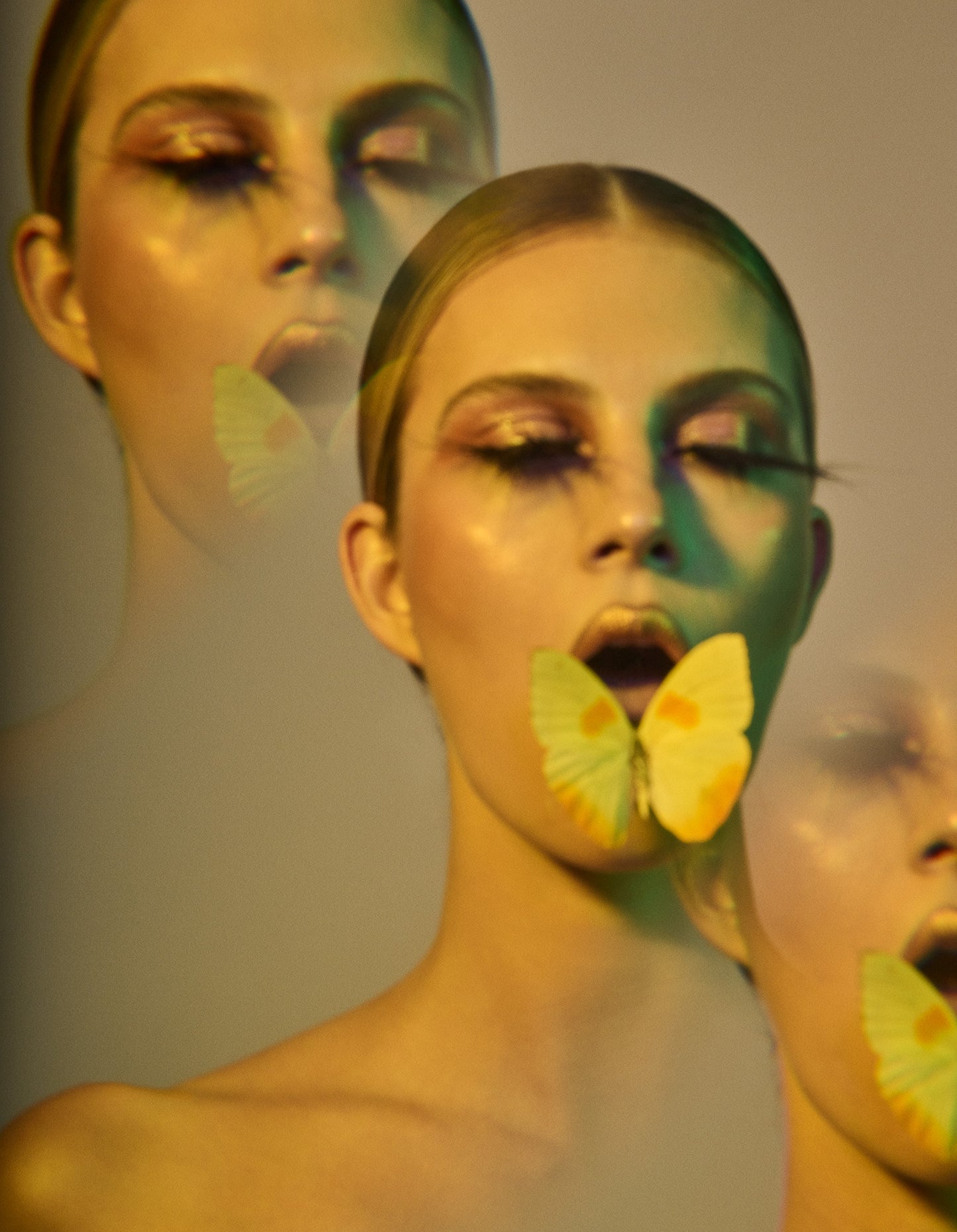 Fine art print of ethereal woman with kaleidoscopic triptych effect and yellow lighting. Portrait of woman with slicked back hair and long eyelashes with yellow moth butterfly in her mouth.