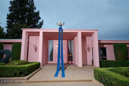 Pink building with a woman sitting on the roof wearing 20 foot long jeans and flexing her biceps.