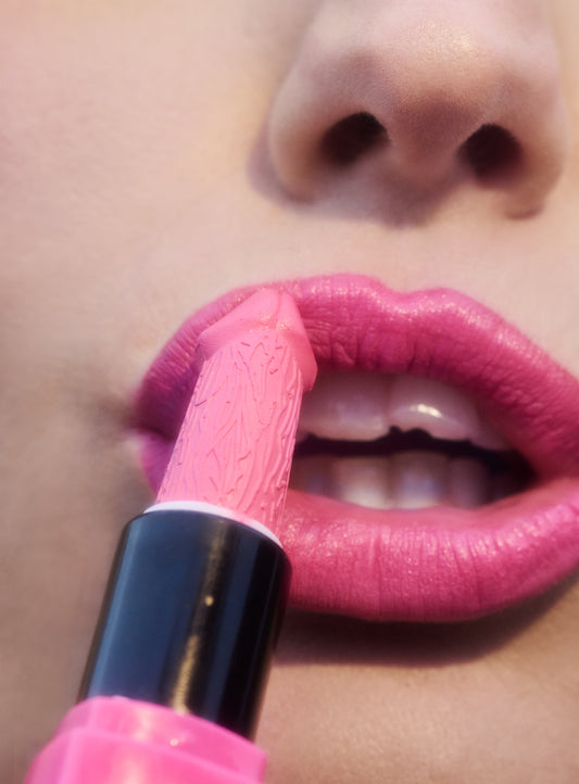 Close-up of woman's pink lips while she applies her lipstick that has a pink phallic penis shaped bullet.