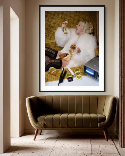 Framed artwork of Amy Taylor, of Amyl and the Sniffers, in a furry coat sitting inside a gold bath tub while yelling on the phone and eating fried chicken.