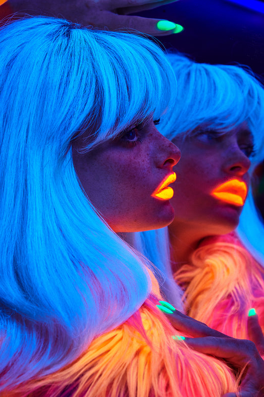 UV glow-in-the-dark beauty editorial of party woman looking into mirror reflection