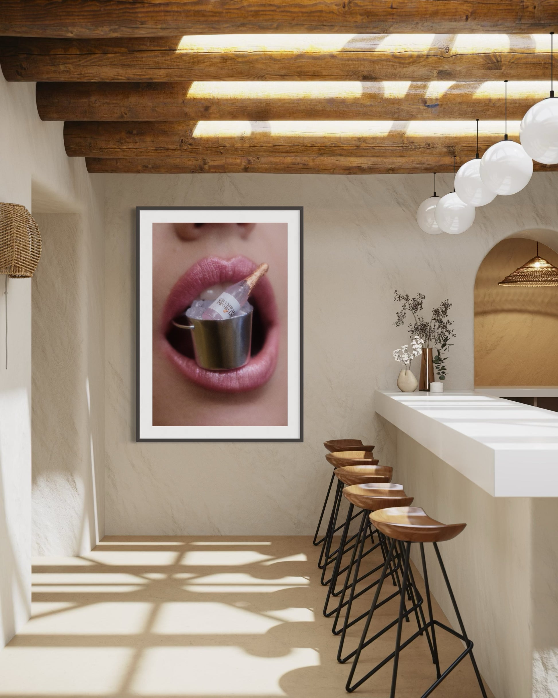 Framed artwork of pink lips holding a miniature bottle of champagne on ice inside a bucket.