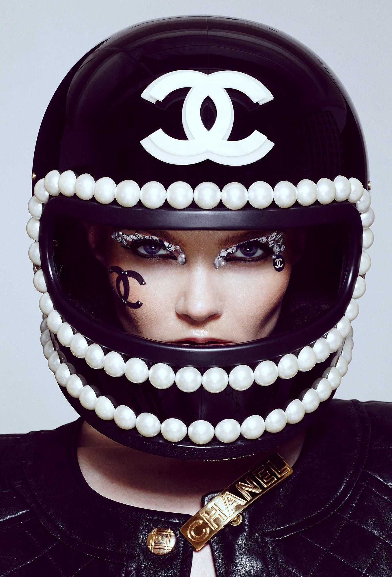 woman girl wearing black chanel logo custom motorcycle luxury designer helmet with oversized pearls and crystal eye makeup with chanel face stickers