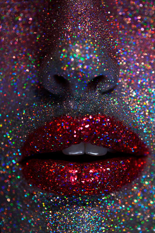 Close-up of a person's lips with ruby red lipstick, surrounded by a face covered in multicolored glitter, emphasizing a vibrant and Avant-garde makeup look.