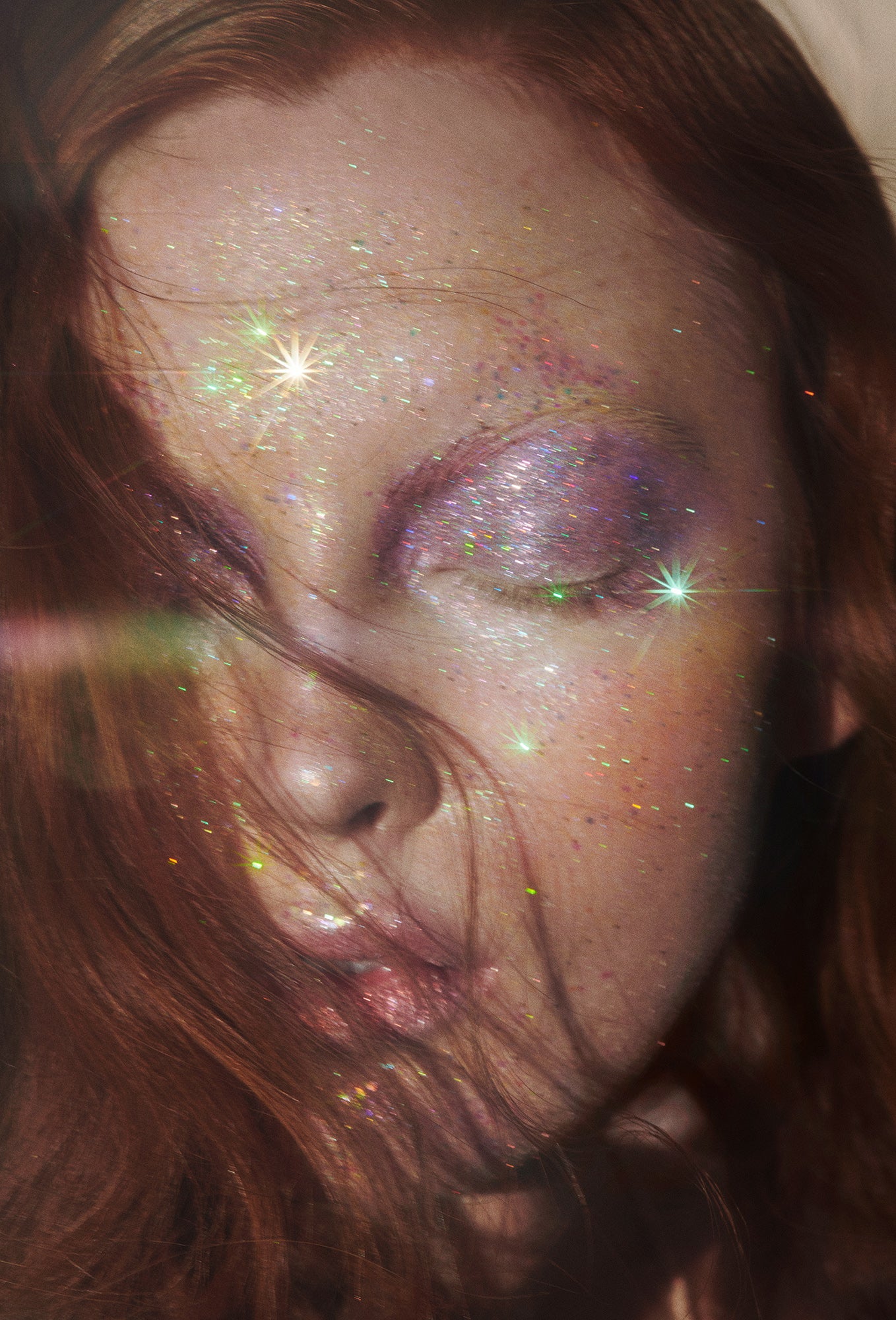 Redhead Ethereal Woman with lilac purple eyeshadow on her closed eyes with glitter all over her skin and starburst lights shimmering and reflecting the glitter.