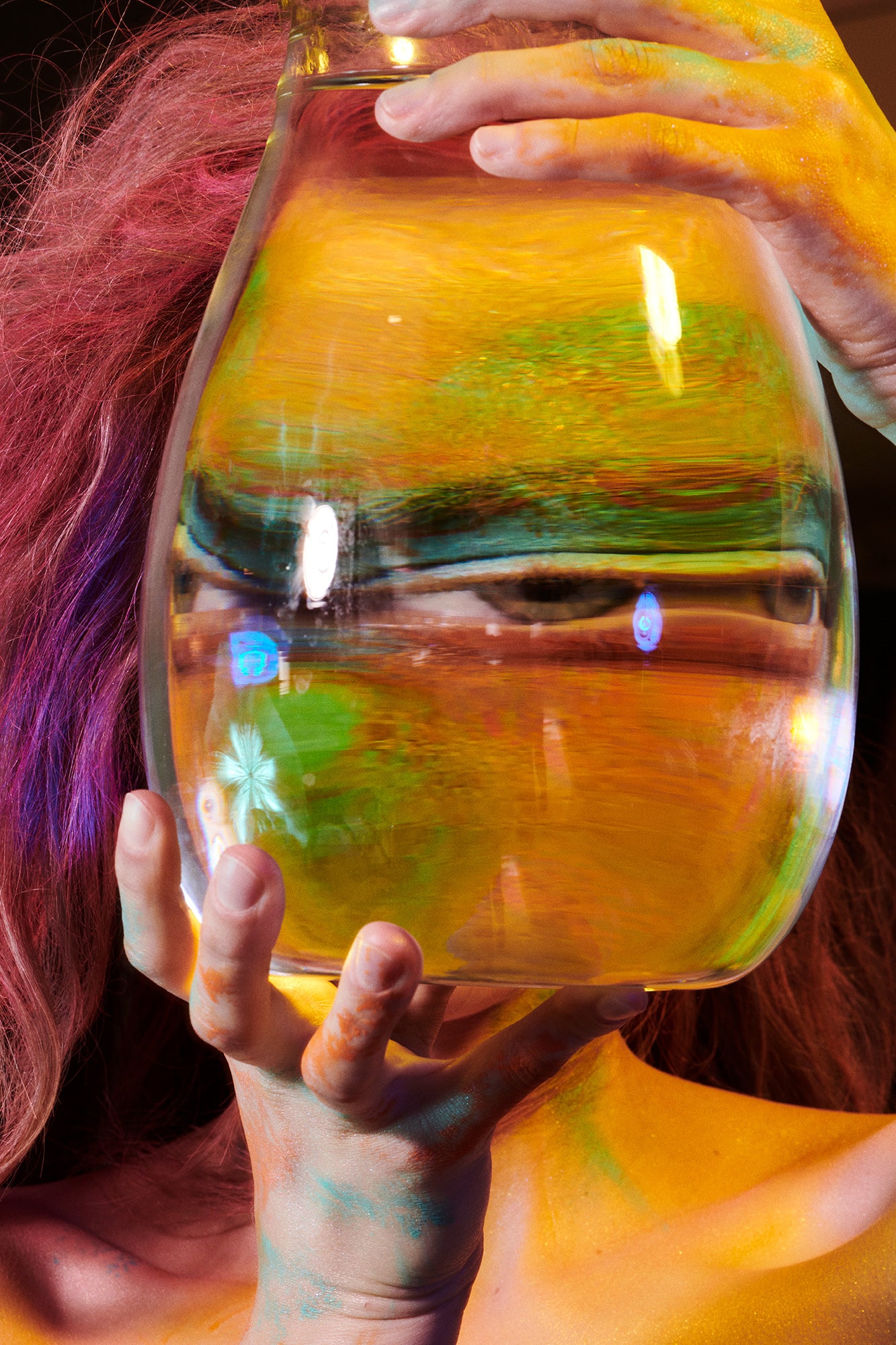 Colorful trippy psychedelic fine art photography of woman looking thrugh a glass of water as her eye is large and  distorted