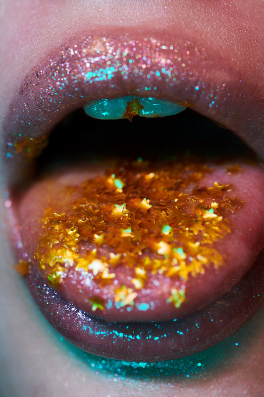 Celebratory New Years holiday close-up beauty editorial of woman's tongue out full of star glitter