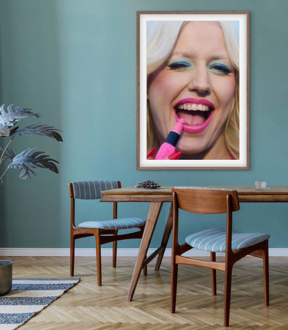 A blue dining room with a large framed art photo of punk singer Amy Taylor (Amyl and the Sniffers) winking and smiling while applying lipstick. The photograph is by renowned photographer Jamie Nelson.