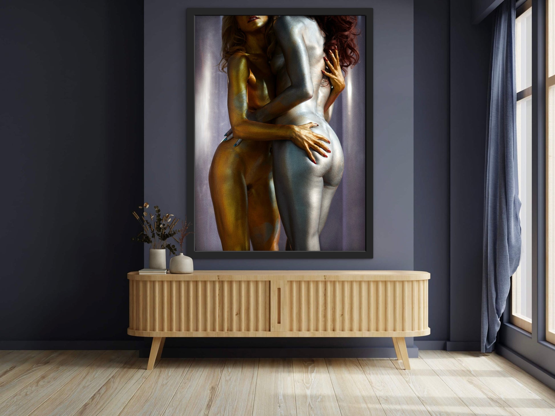 Framed artwork of nude women covered in metallic body paint while embracing in a messy hug.