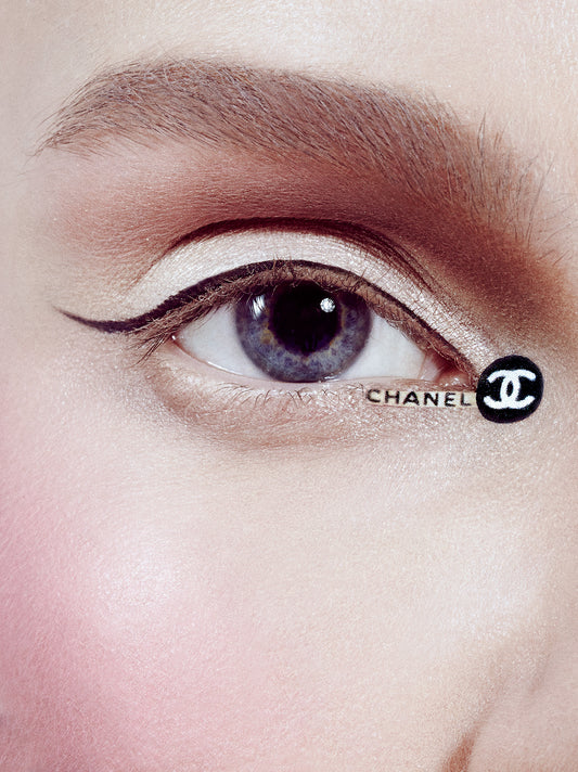 macro photography of woman's blue eye with thin black eyeliner and chanel designer eye booger logo