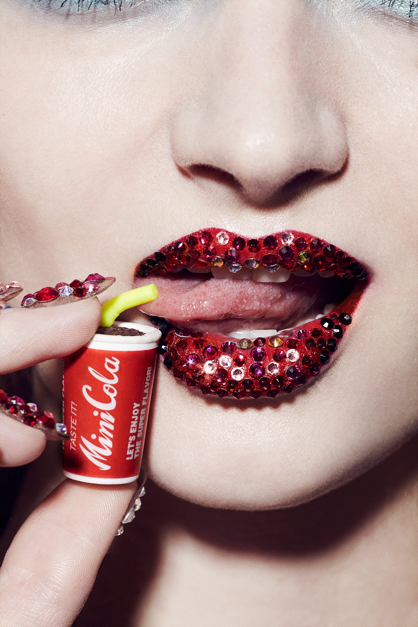 Woman with crystal glitter red lips drinking tiny mini Coca Cola bottle