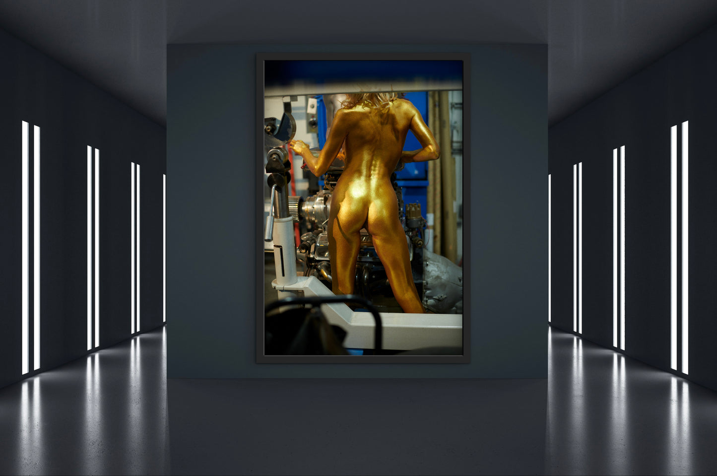 Framed artwork of an athletic woman who is nude and painted entirely gold  working with machinery  in an industrial setting.