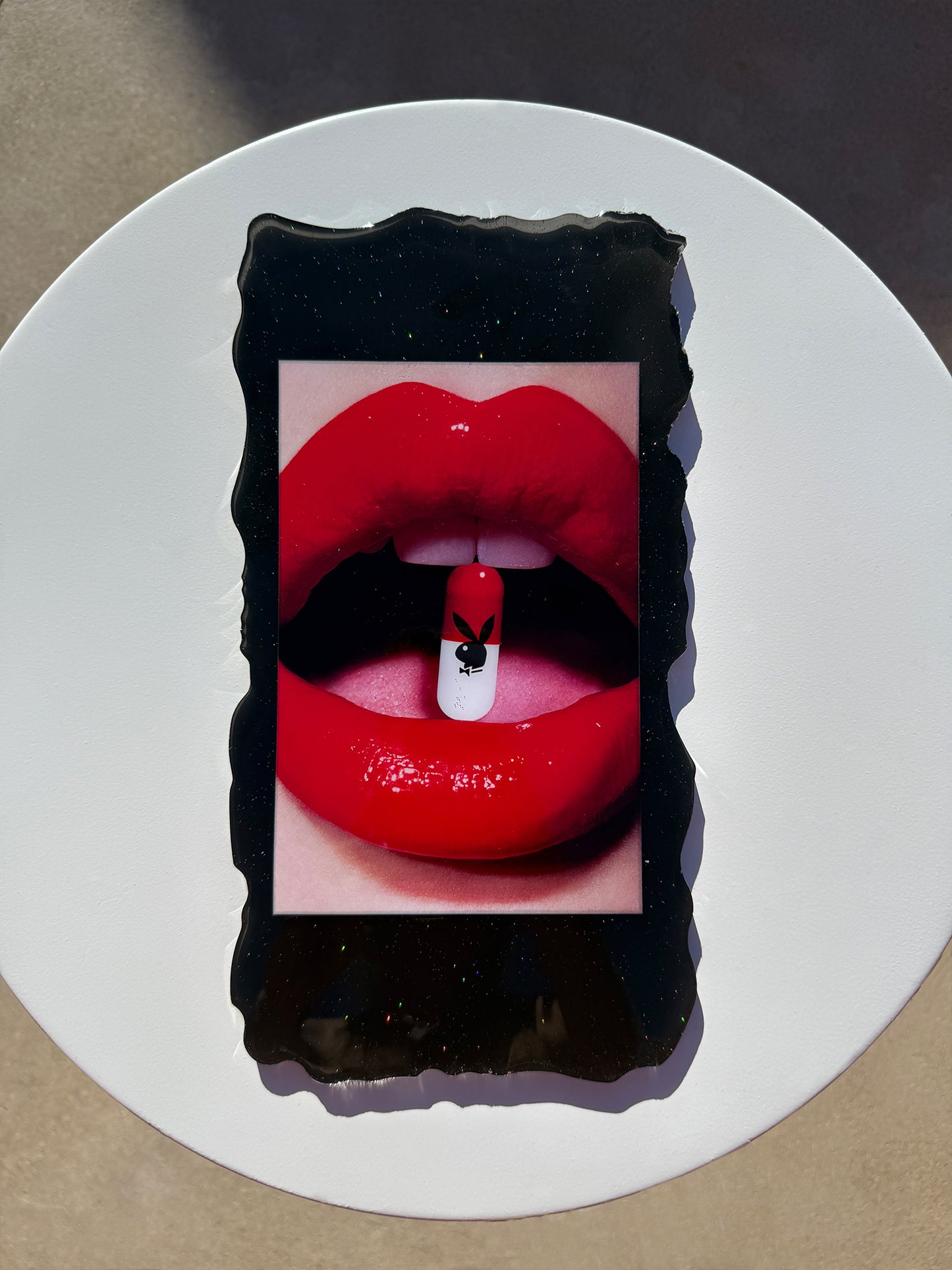 Black trinket tray with a design of red lips and a black and Playboy bunny pill in the mouth.