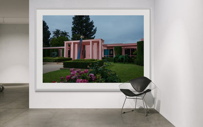 Framed photograph of a pink building with greenery in a minimalistic room.