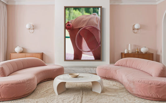 A modern pink living room with a large framed photograph of a retro style woman bending over to serve tennis as her butt  is exposed.