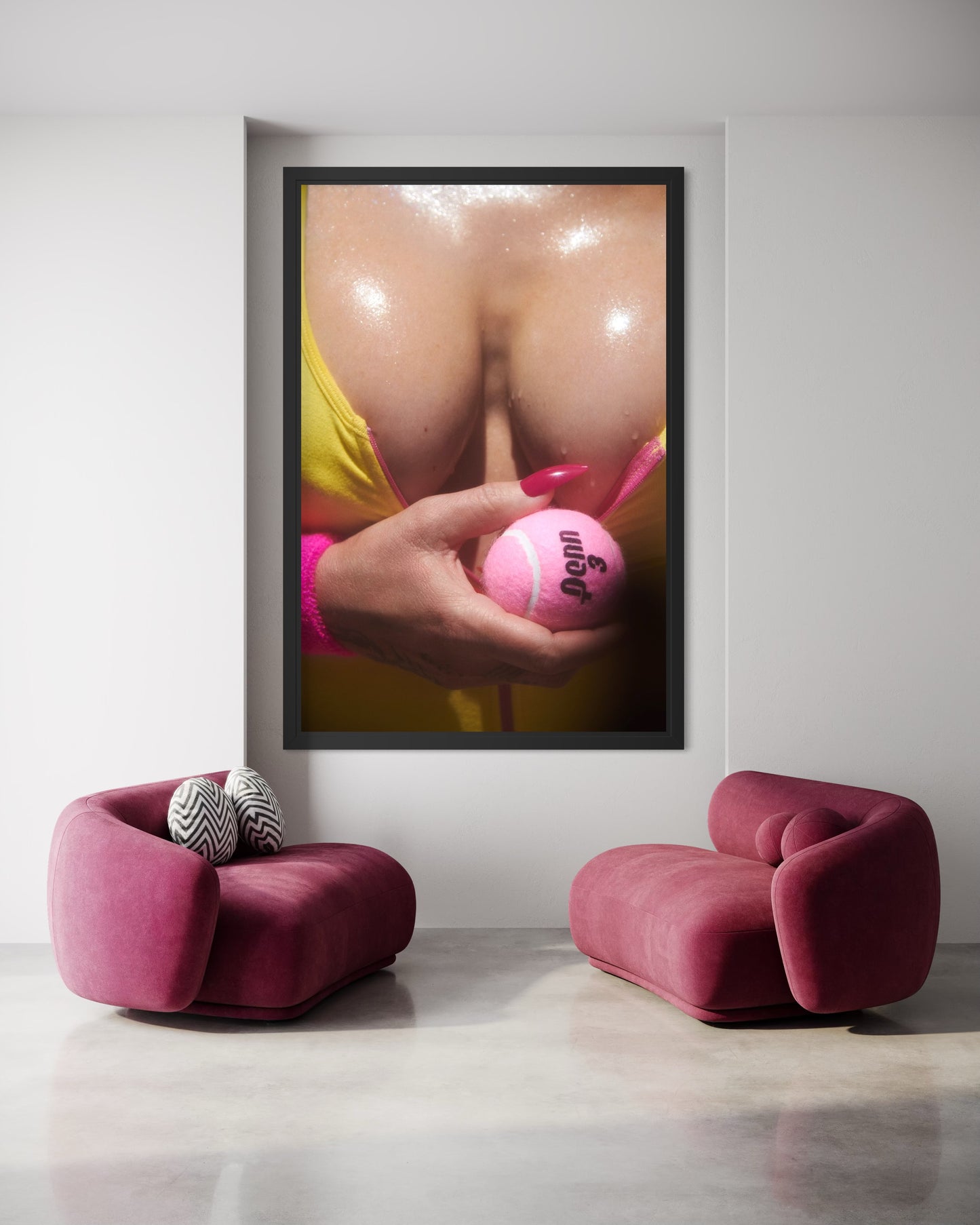 A modern room with a large framed artwork of a woman's sweaty breasts as she holds a pink tennis ball.