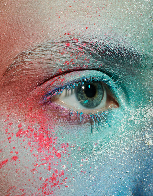 Close-up macro beauty portrait of Woman's eye with moon dust powder splash artistic makeup in red, white, and blue teal hues